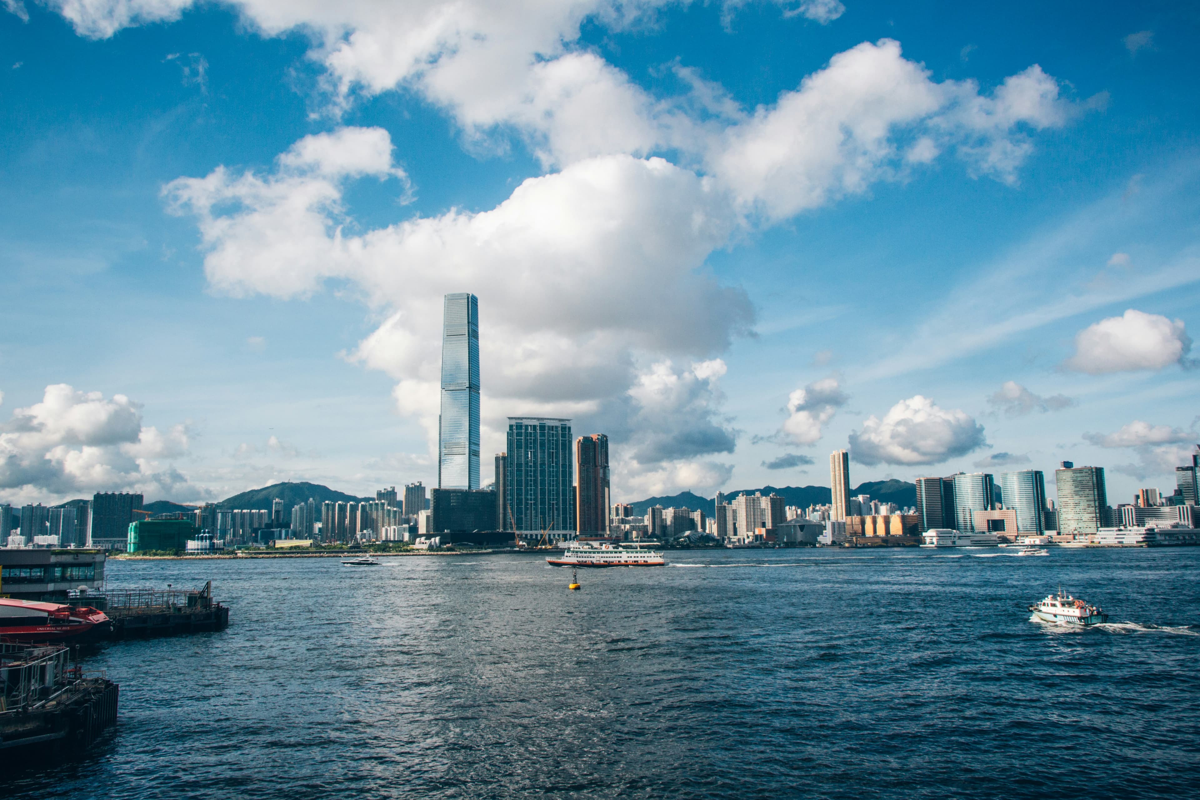 Um pequeno barco em um corpo de agua com Hong Kong ao fundo